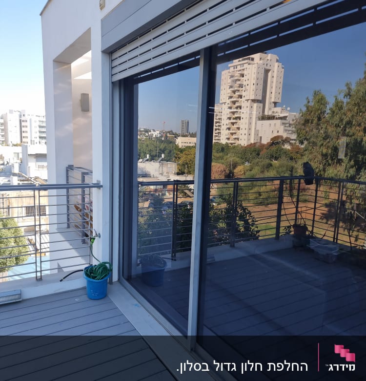 חלון זכוכית גדול עם השתקפות של בניינים ועצים.